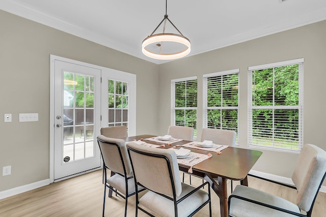 dining space featuring baseboards, ornamental molding, a wealth of natural light, and light wood-type flooring