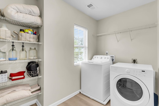 laundry area featuring laundry area, baseboards, wood finished floors, visible vents, and washing machine and dryer