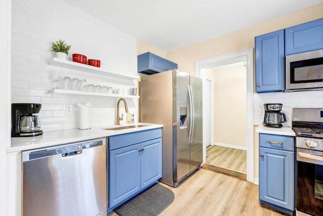 kitchen with blue cabinets, sink, decorative backsplash, light wood-type flooring, and appliances with stainless steel finishes