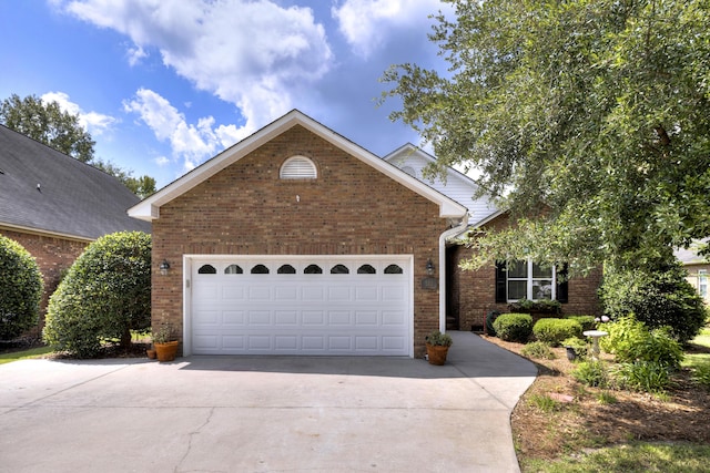view of front of house with brick siding, an attached garage, and concrete driveway