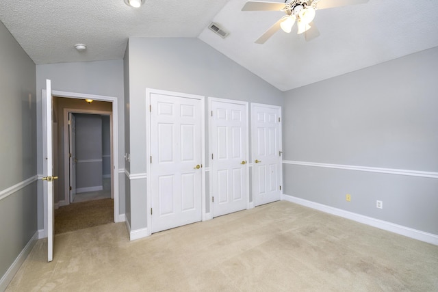 unfurnished bedroom featuring two closets, baseboards, light carpet, and vaulted ceiling