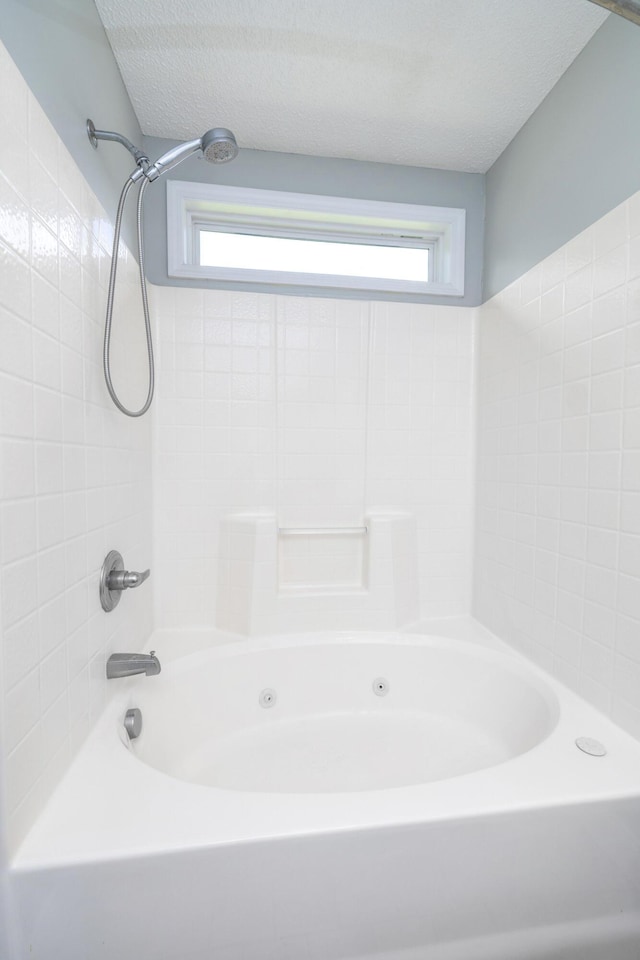 bathroom with washtub / shower combination and a textured ceiling