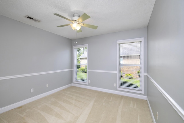 spare room featuring light carpet, visible vents, baseboards, and a ceiling fan