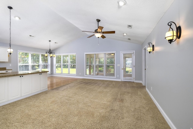 unfurnished living room with light carpet, ceiling fan with notable chandelier, lofted ceiling, and visible vents