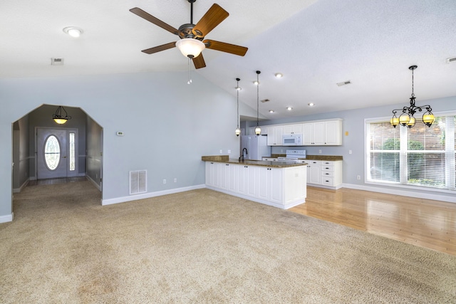 kitchen featuring white appliances, visible vents, open floor plan, and dark countertops