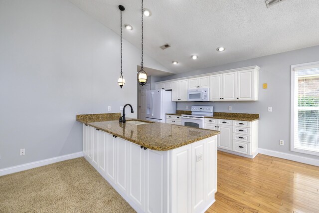 kitchen with visible vents, a sink, white appliances, a peninsula, and vaulted ceiling