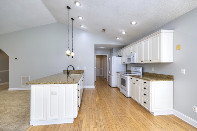 kitchen featuring white appliances, a peninsula, white cabinetry, visible vents, and a sink
