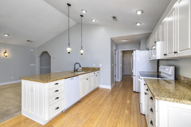 kitchen featuring visible vents, a sink, white appliances, a peninsula, and white cabinetry