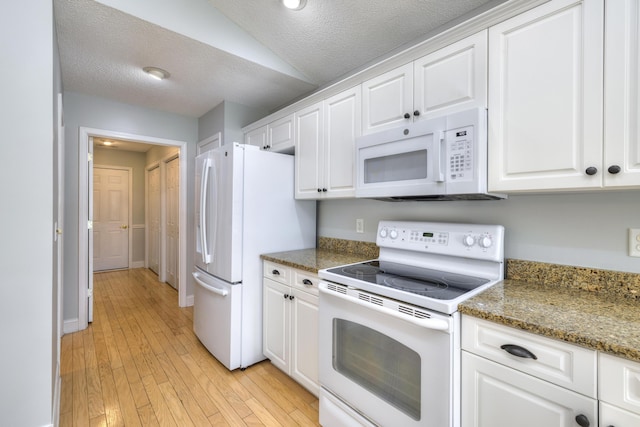 kitchen featuring white appliances, a textured ceiling, vaulted ceiling, white cabinets, and light wood finished floors