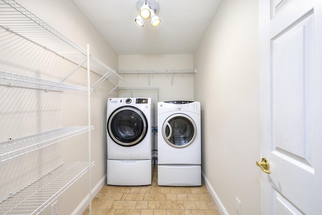 laundry room with laundry area, baseboards, a textured ceiling, and washer and clothes dryer