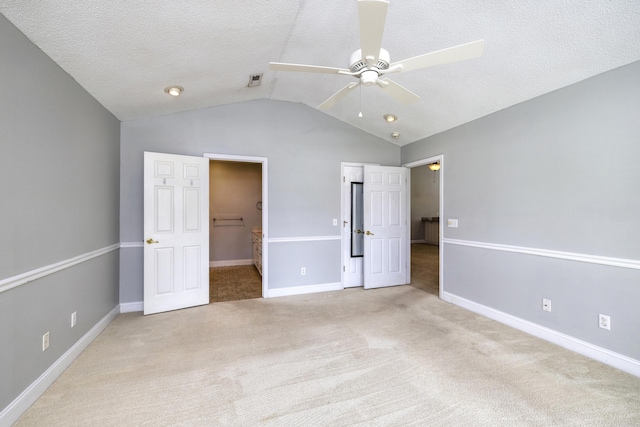 unfurnished bedroom featuring baseboards, a spacious closet, a textured ceiling, carpet floors, and lofted ceiling