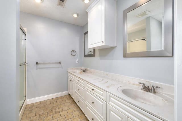 bathroom with double vanity, visible vents, a sink, and baseboards