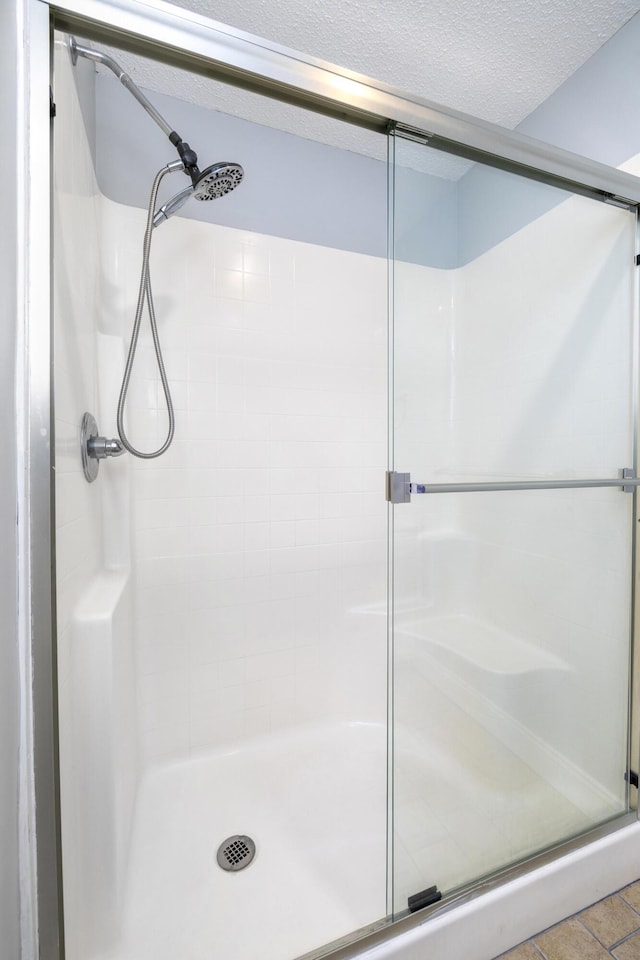bathroom with a shower stall and a textured ceiling