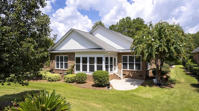 rear view of property featuring entry steps, a yard, a patio area, crawl space, and brick siding