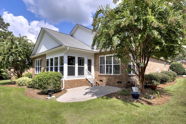 back of house featuring brick siding, a lawn, a patio, and crawl space