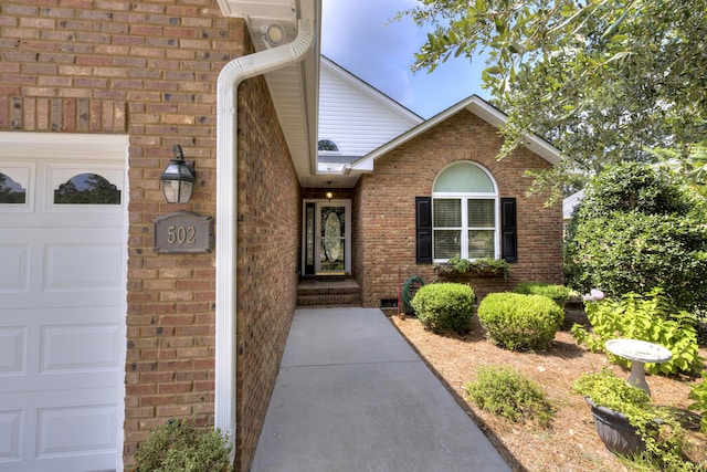 property entrance featuring a garage and brick siding