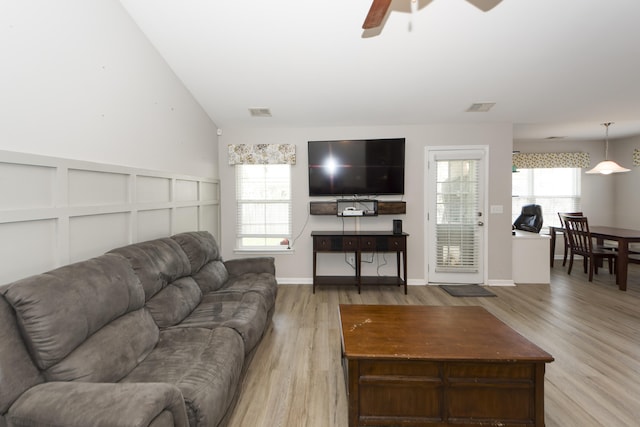 living room with ceiling fan, lofted ceiling, light wood-type flooring, and a healthy amount of sunlight