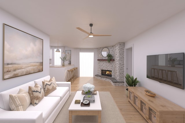 living room featuring ceiling fan, light hardwood / wood-style floors, and a stone fireplace