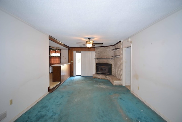 unfurnished living room with ceiling fan, dark carpet, ornamental molding, and a textured ceiling