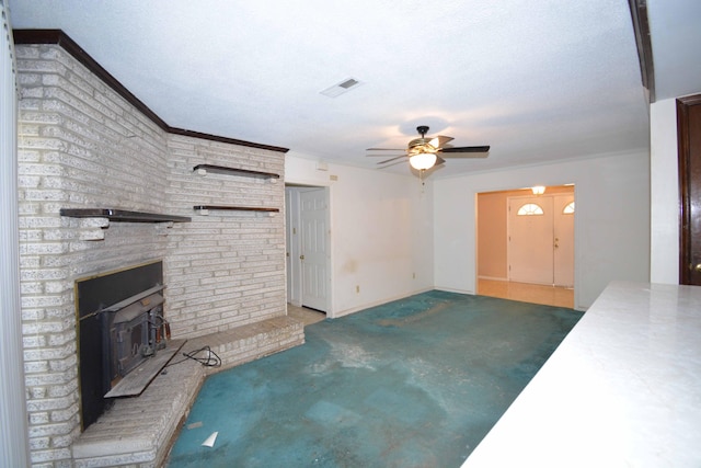 unfurnished living room with a wood stove, carpet flooring, ceiling fan, ornamental molding, and a textured ceiling