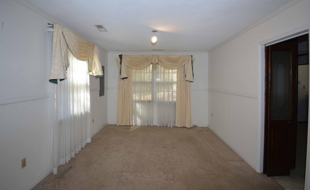 unfurnished room featuring a textured ceiling, crown molding, and light carpet