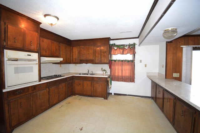 kitchen with white appliances, crown molding, sink, a textured ceiling, and kitchen peninsula