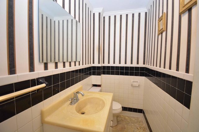 bathroom featuring vanity, tile patterned floors, crown molding, toilet, and tile walls