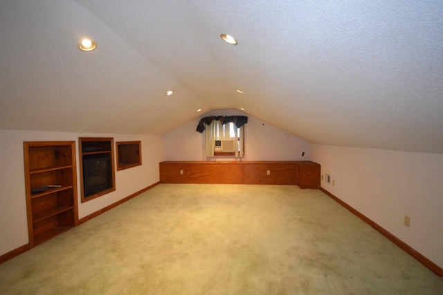 additional living space featuring a textured ceiling, light colored carpet, and vaulted ceiling