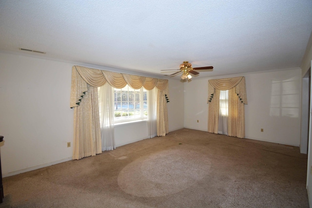 empty room with carpet flooring, ceiling fan, a textured ceiling, and ornamental molding