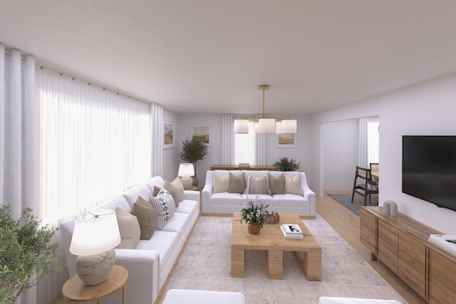 living room with a wealth of natural light, light hardwood / wood-style floors, and a notable chandelier