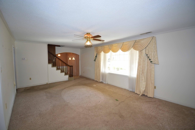 unfurnished room with a textured ceiling, ceiling fan, ornamental molding, and light carpet