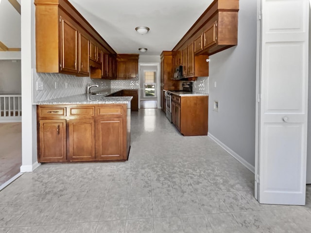 kitchen featuring sink, light stone counters, backsplash, and appliances with stainless steel finishes