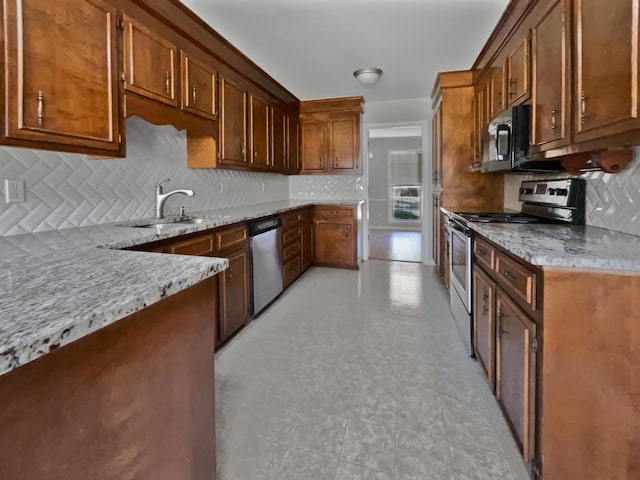 kitchen featuring stainless steel appliances, light stone counters, and tasteful backsplash