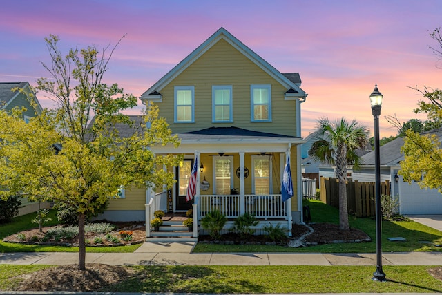 view of front facade featuring a lawn, a garage, and covered porch