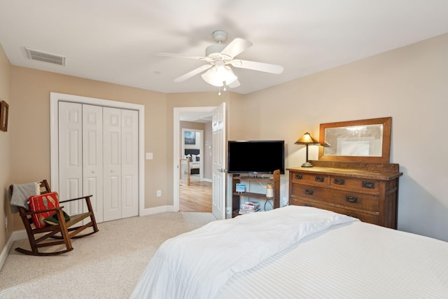 bedroom with baseboards, visible vents, light colored carpet, ceiling fan, and a closet