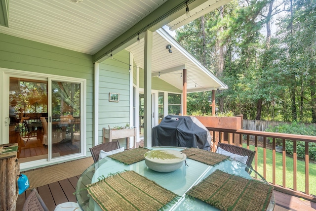 wooden terrace featuring outdoor dining area, a grill, and fence