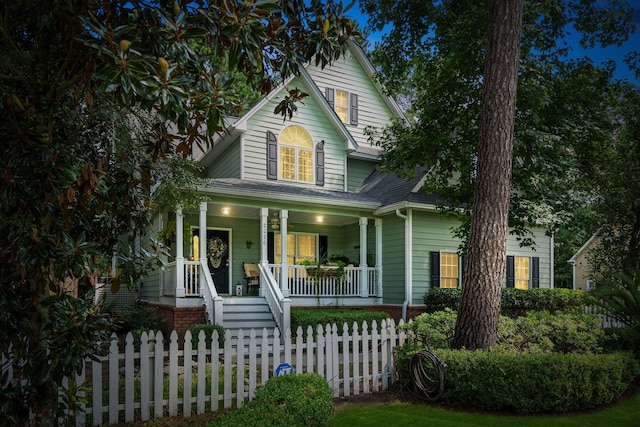 view of front of house with roof with shingles, a porch, and a fenced front yard