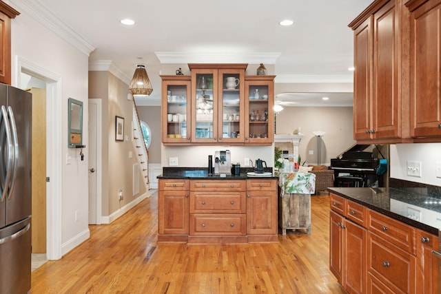 kitchen featuring light wood finished floors, brown cabinetry, glass insert cabinets, and freestanding refrigerator