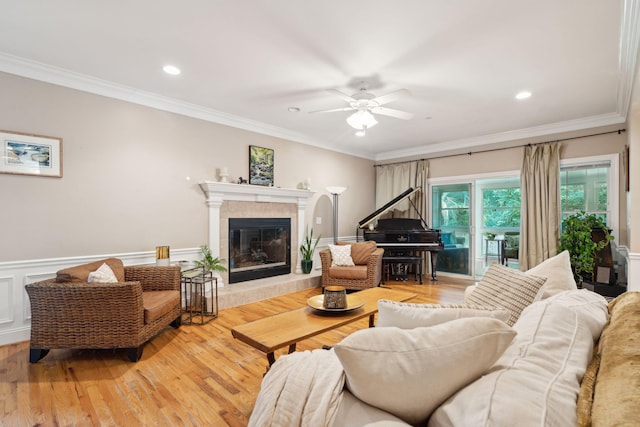 living room featuring ornamental molding, wainscoting, a fireplace, and light wood finished floors