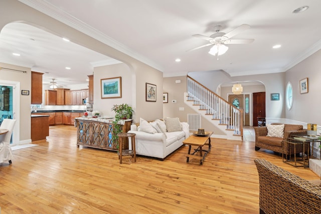 living area with arched walkways, ornamental molding, stairs, and light wood-style floors