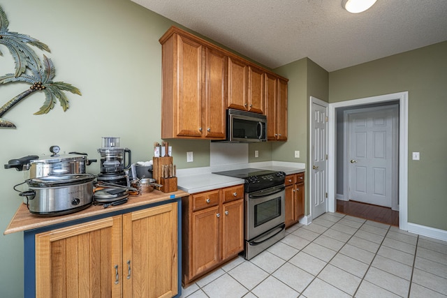 105 Northpark Ave, Summerville, SC 29485 - kitchen with appliances with stainless steel finishes, light countertops, light tile patterned floors, brown cabinets, and a textured ceiling