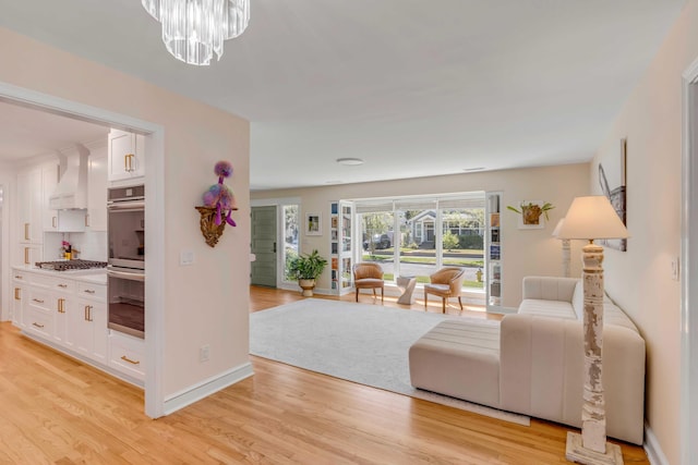 living area with a chandelier, light wood finished floors, and baseboards