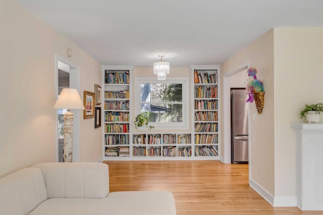 living area with a notable chandelier, light wood-style flooring, and baseboards