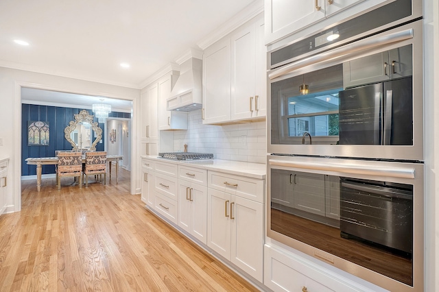 kitchen featuring premium range hood, white cabinetry, light wood-style flooring, and light countertops