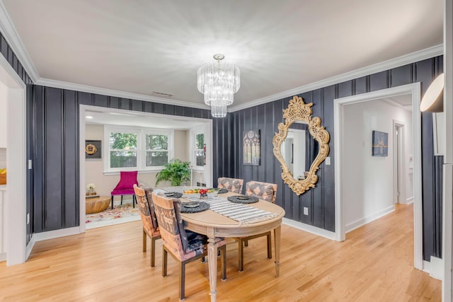 dining area featuring light wood-style floors, a notable chandelier, crown molding, and visible vents