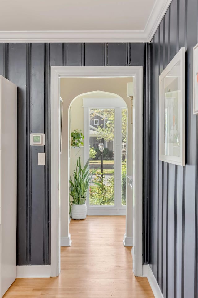 foyer featuring light wood-style flooring, arched walkways, and crown molding