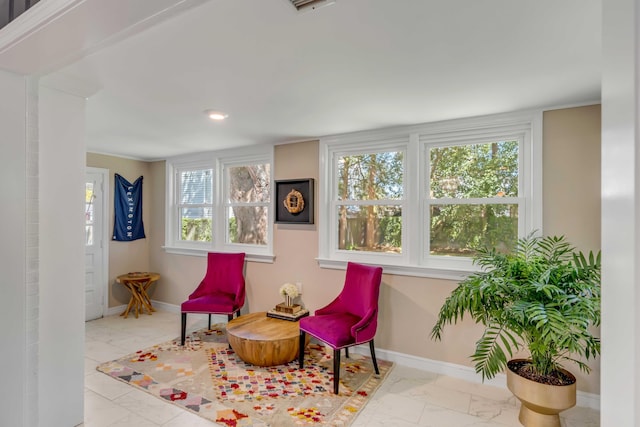 living area featuring marble finish floor and baseboards