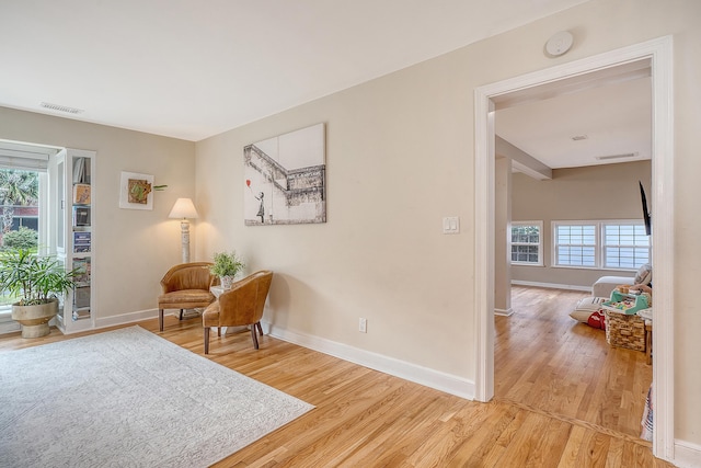 living area with light wood finished floors, visible vents, and baseboards