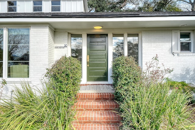 doorway to property with board and batten siding and brick siding