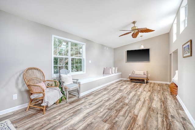 living area featuring a ceiling fan, vaulted ceiling, baseboards, and wood finished floors